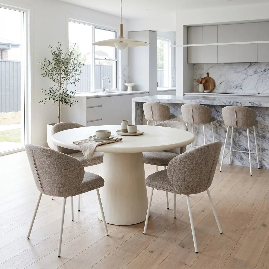 Modern kitchen with round dining table and chairs, marble countertop, and large windows.