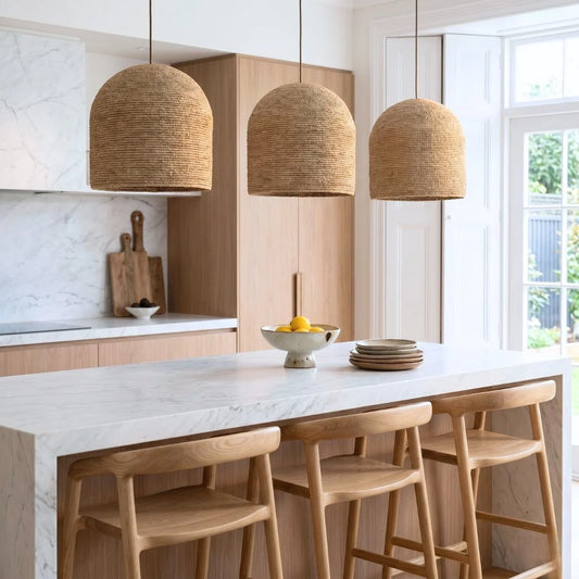 Modern kitchen with marble island, wooden stools, and large oversized woven pendant from sun republic.