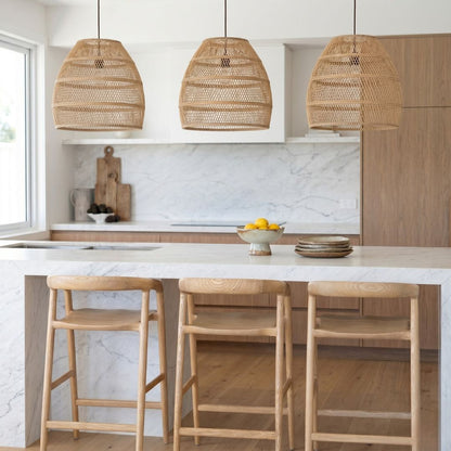 Modern kitchen with marble island, wooden stools, and wicker pendant lights.