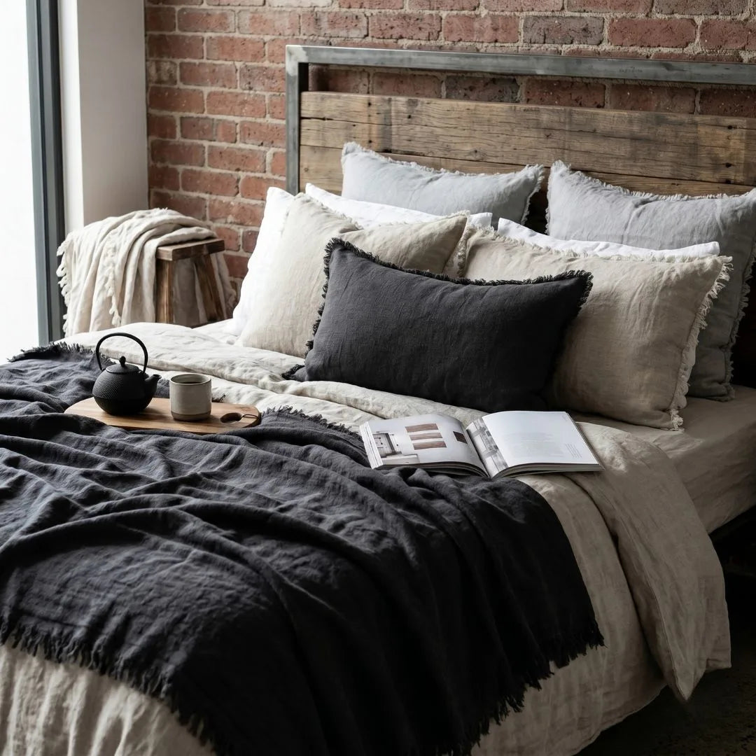 Cozy bedroom with a bed featuring pillows and a blanket, next to a brick wall.