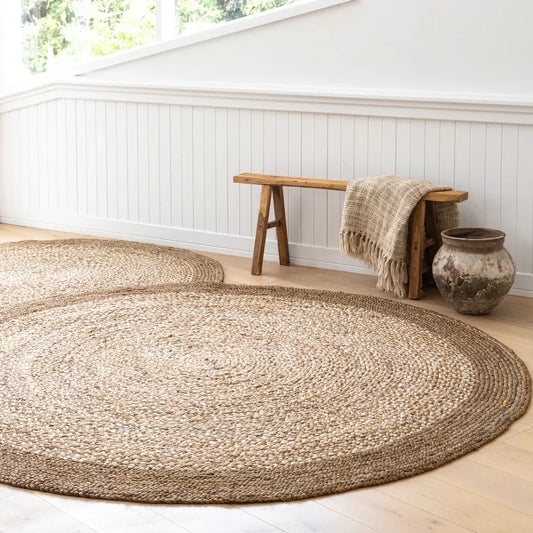 Round jute rug in a room with a wooden bench and vase.