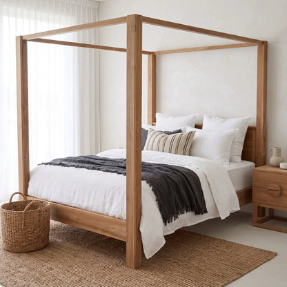 A light natural wood four-poster canopy bed styled with white bedding, a dark gray throw blanket, and a striped accent pillow, set in a bright, modern bedroom next to a matching wood nightstand.