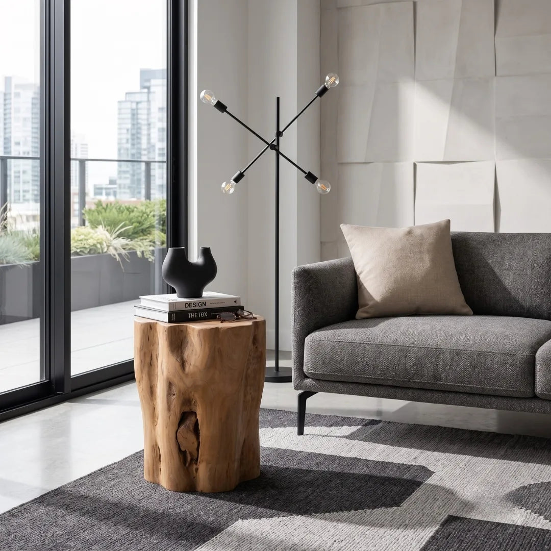 A rustic natural wood side table styled in a modern living room next to a gray sofa and a black starburst floor lamp.