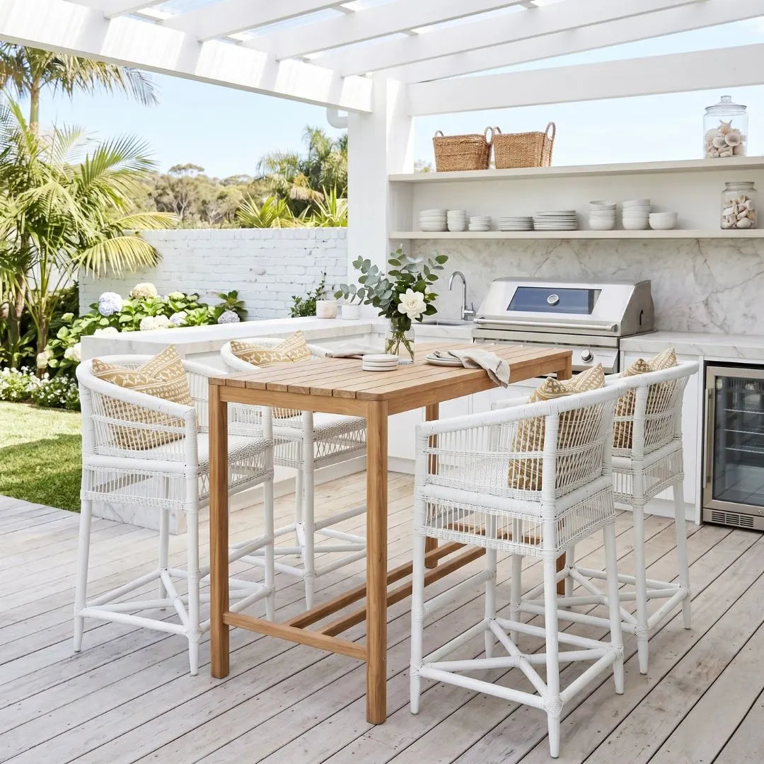 Outdoor patio with wooden table and white chairs, surrounded by a kitchen area.