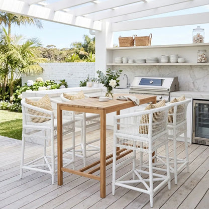 Outdoor patio with wooden table and white chairs, surrounded by a kitchen area.
