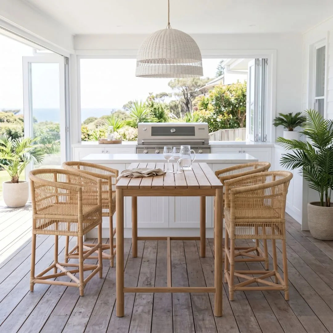 Outdoor dining area with wooden table and chairs on a deck, overlooking greenery.
