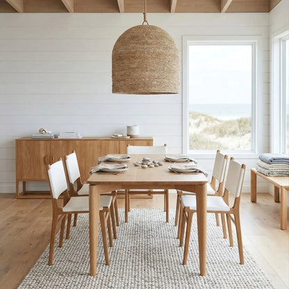 Dining room with wooden table and chairs, wicker pendant light, and large windows.