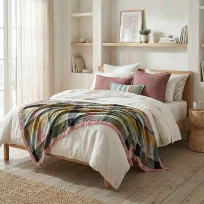 Bedroom with a bed featuring a colorful blanket and pillows, wooden floor, and shelves.