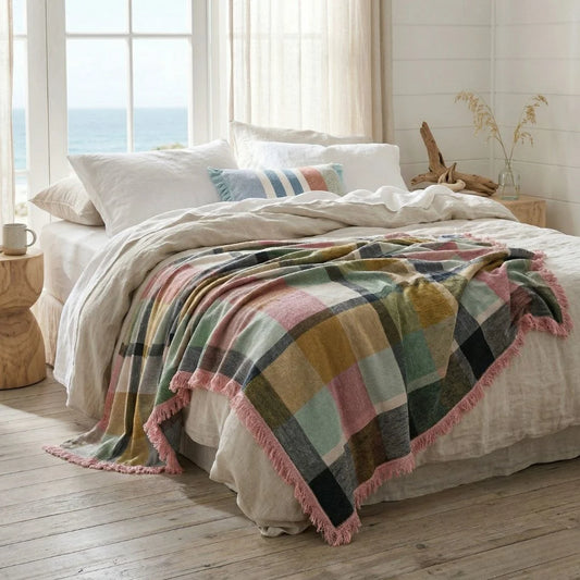 Bedroom with a bed covered by a plaid blanket and pillows.