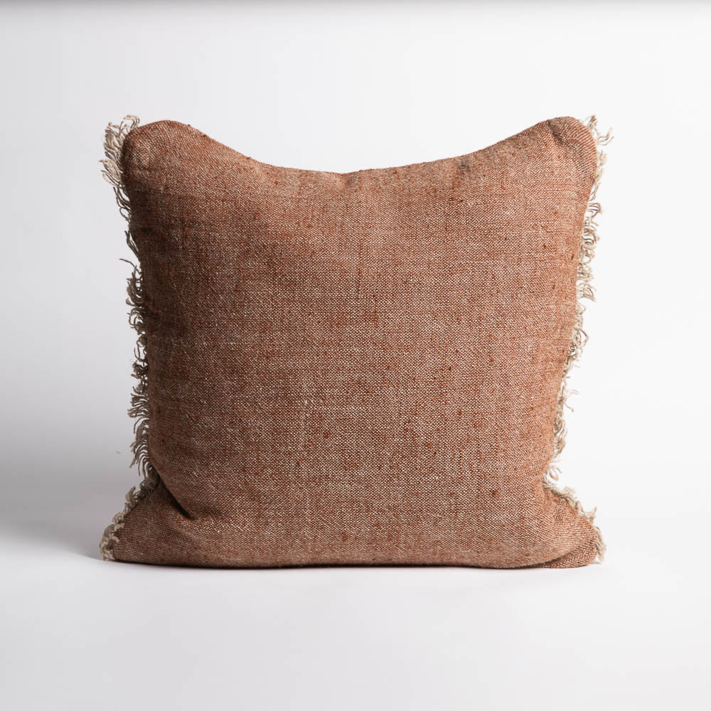 Brown textured pillow with frayed edges on a white background