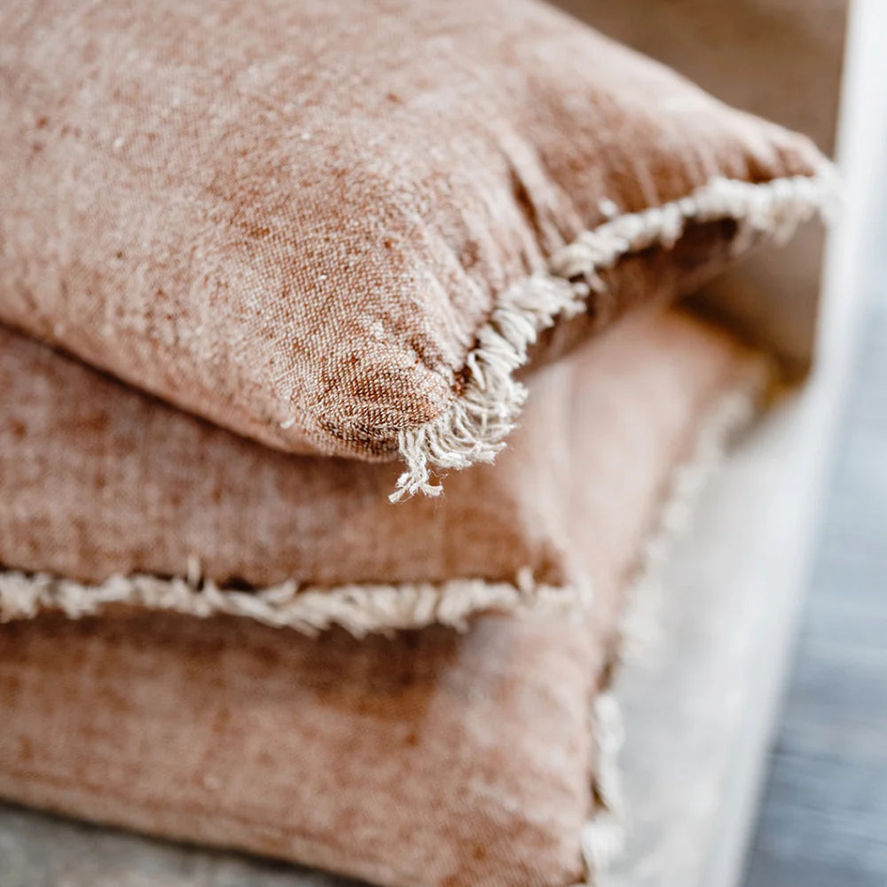 Stack of brown textured pillows on a neutral background