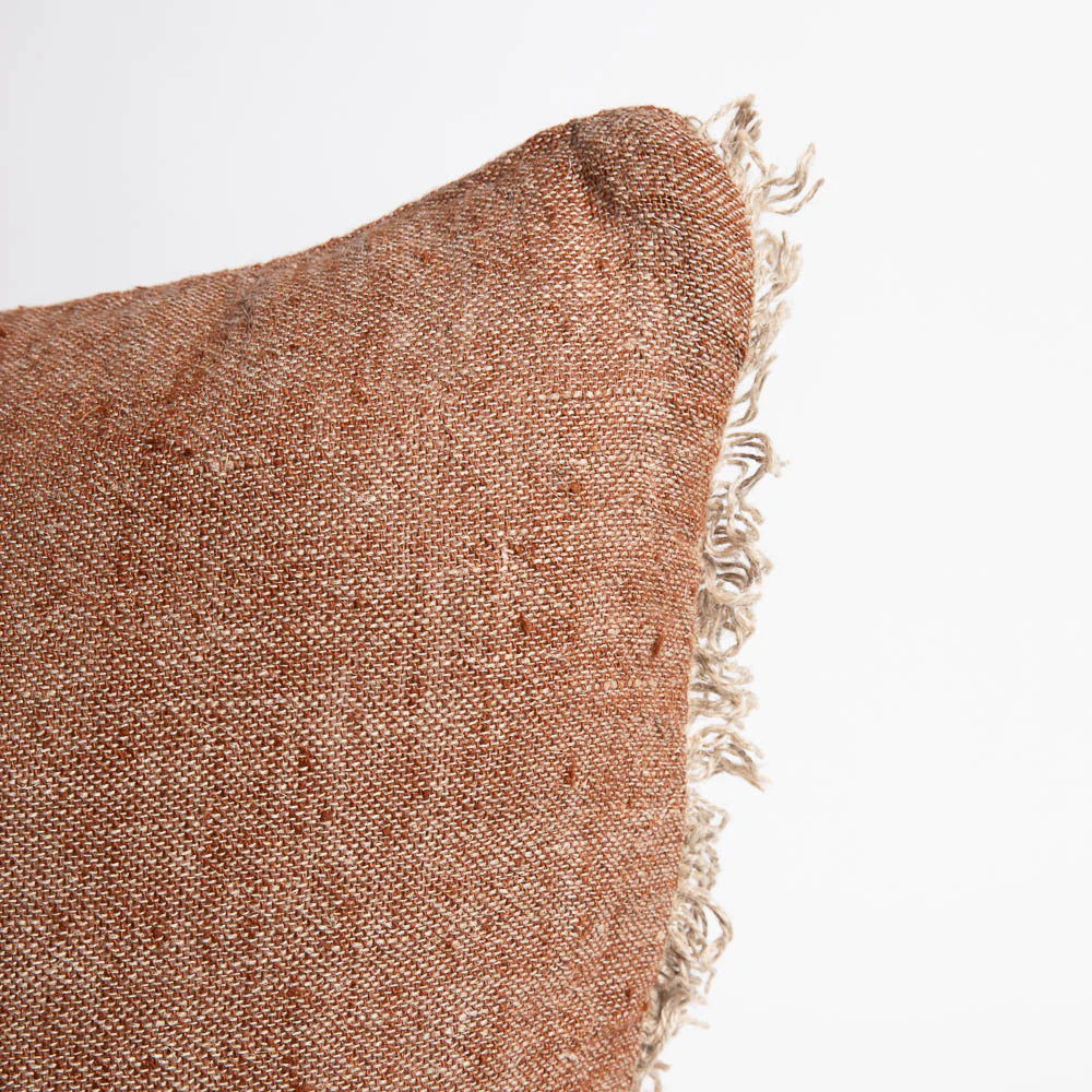 Textured brown pillow with frayed edge on a white background
