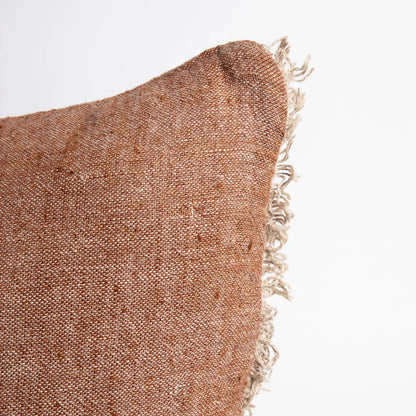Textured brown pillow with frayed edge on a white background