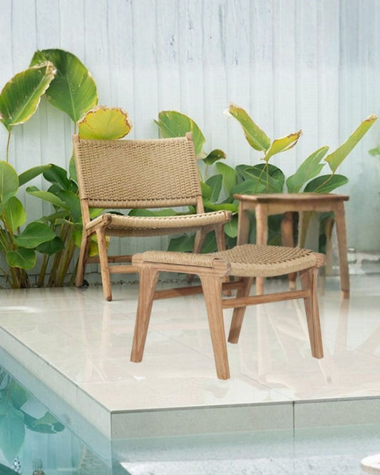 Wicker chair and ottoman by a pool with plants in the background