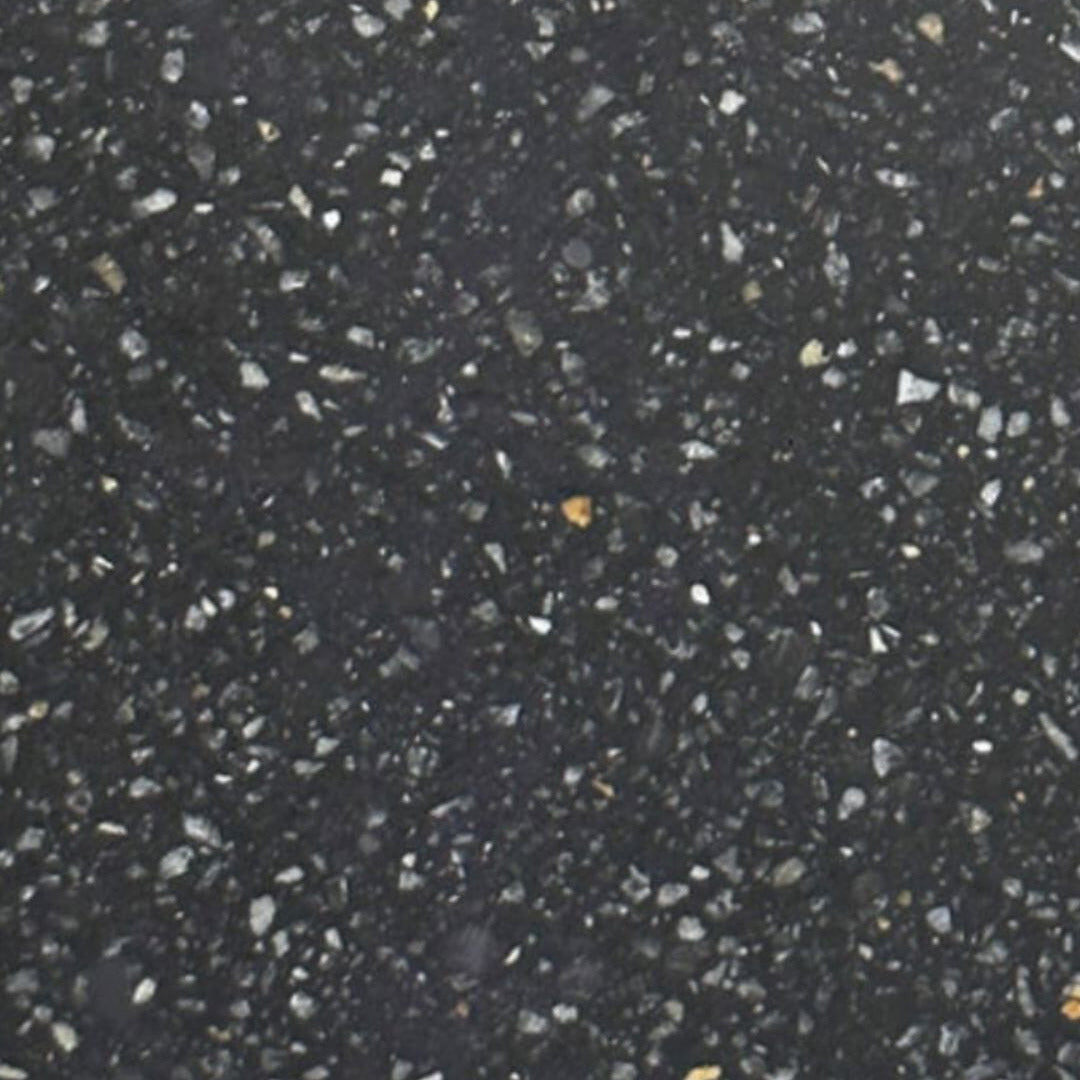 A close-up texture of a black speckled stone or concrete surface with small white, gray, and minor orange flecks throughout.