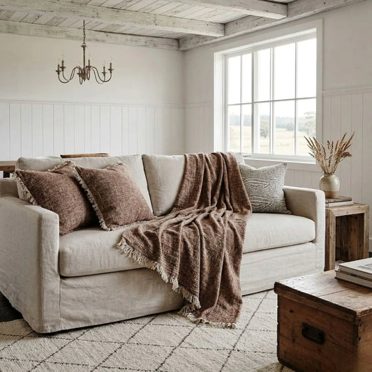 Cozy living room with beige sofa, brown throw blanket, and wooden coffee table.