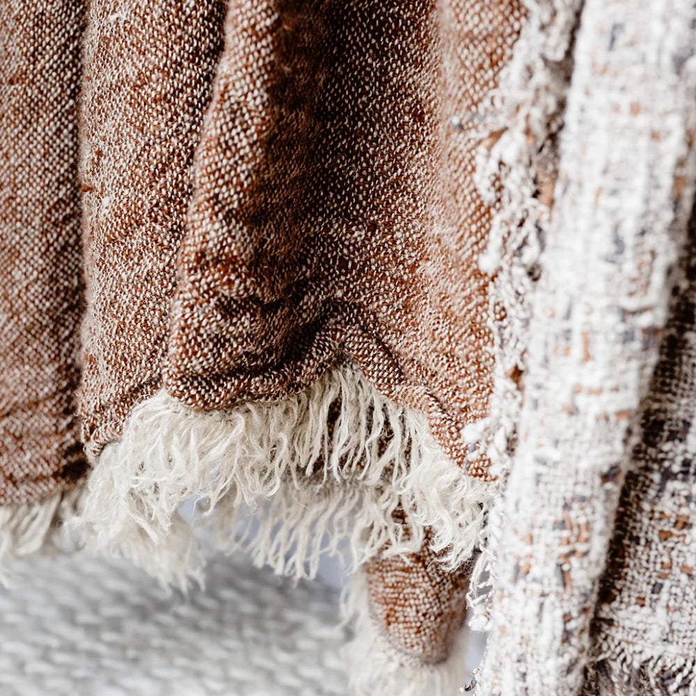 Close-up of a textured blanket with fringes on a soft surface