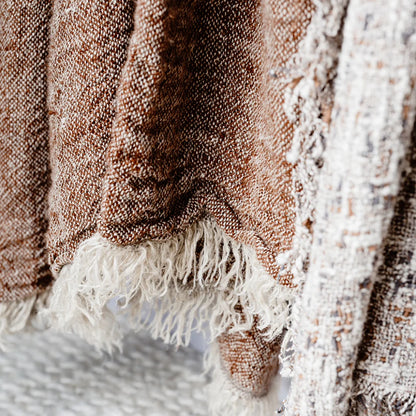 Close-up of a textured blanket with fringes on a soft surface