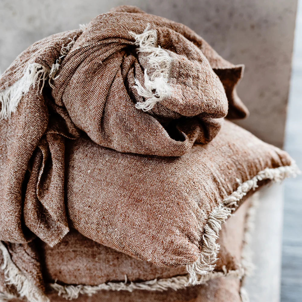 Brown textured fabric with frayed edges on a neutral background