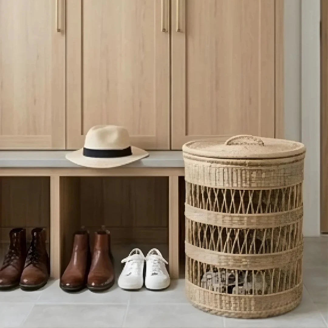 Wooden wardrobe with a bench, shoes, and a hat next to a wicker laundry basket.