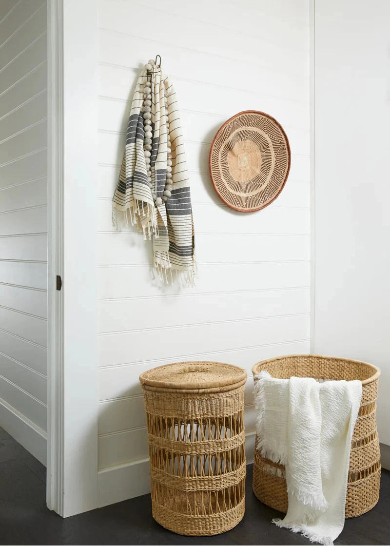 Cane laundry baskets with towels against a white wall