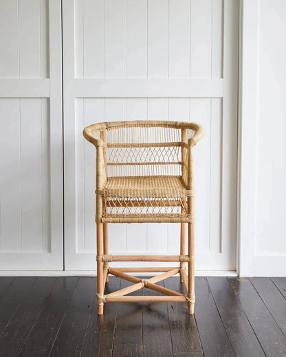 Malawi Cane Counter Stool against a white paneled wall