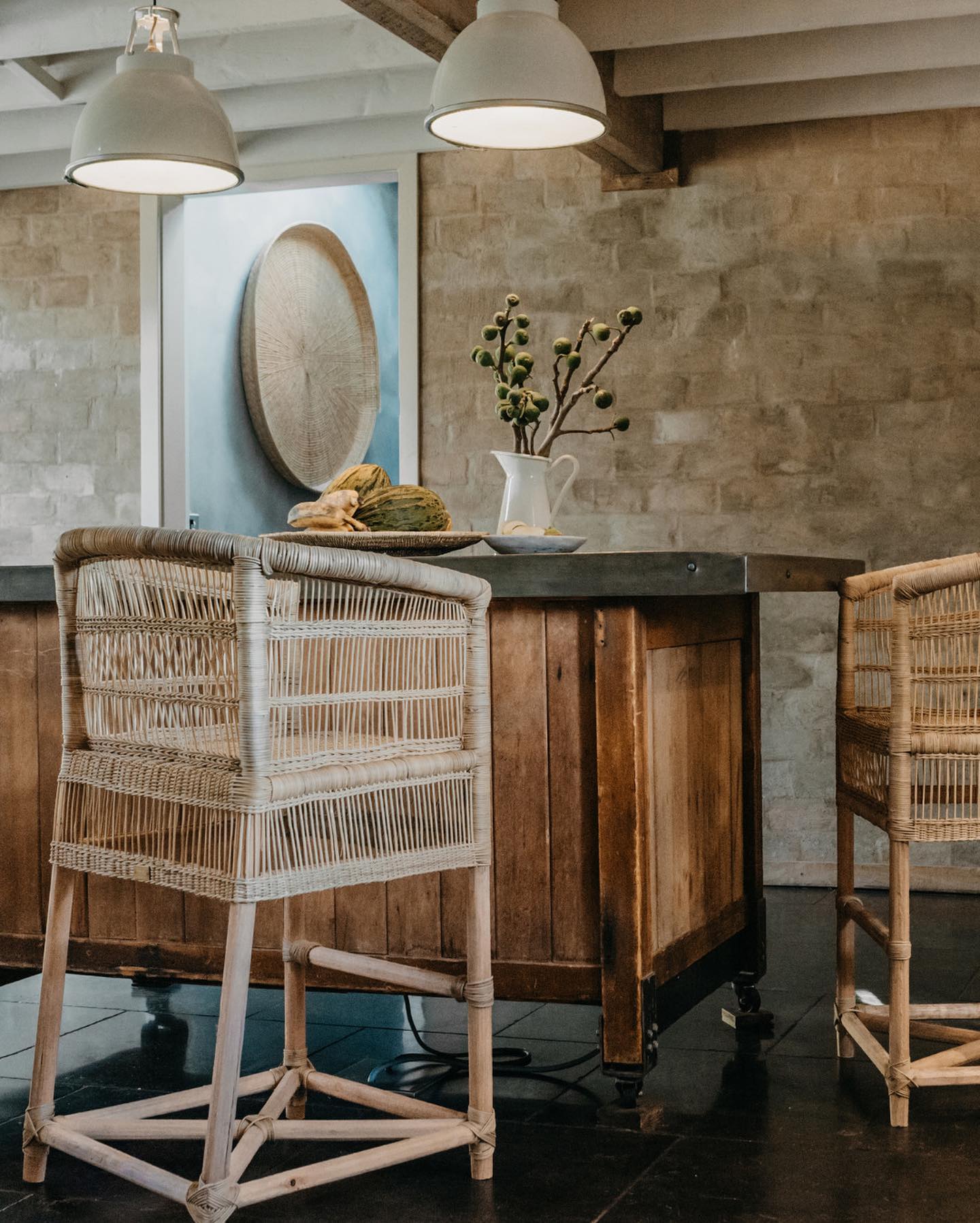 Wooden kitchen island with wicker chairs in a rustic setting