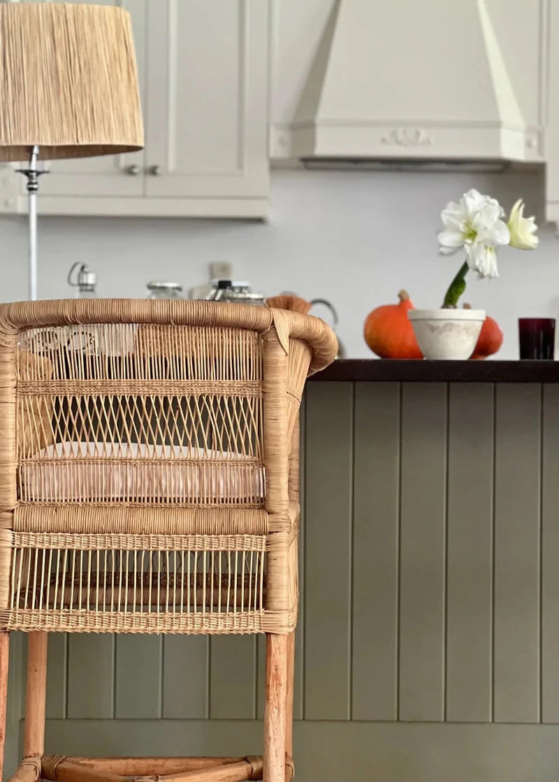 Kitchen interior with a wicker cart, cabinets, and decorative items.