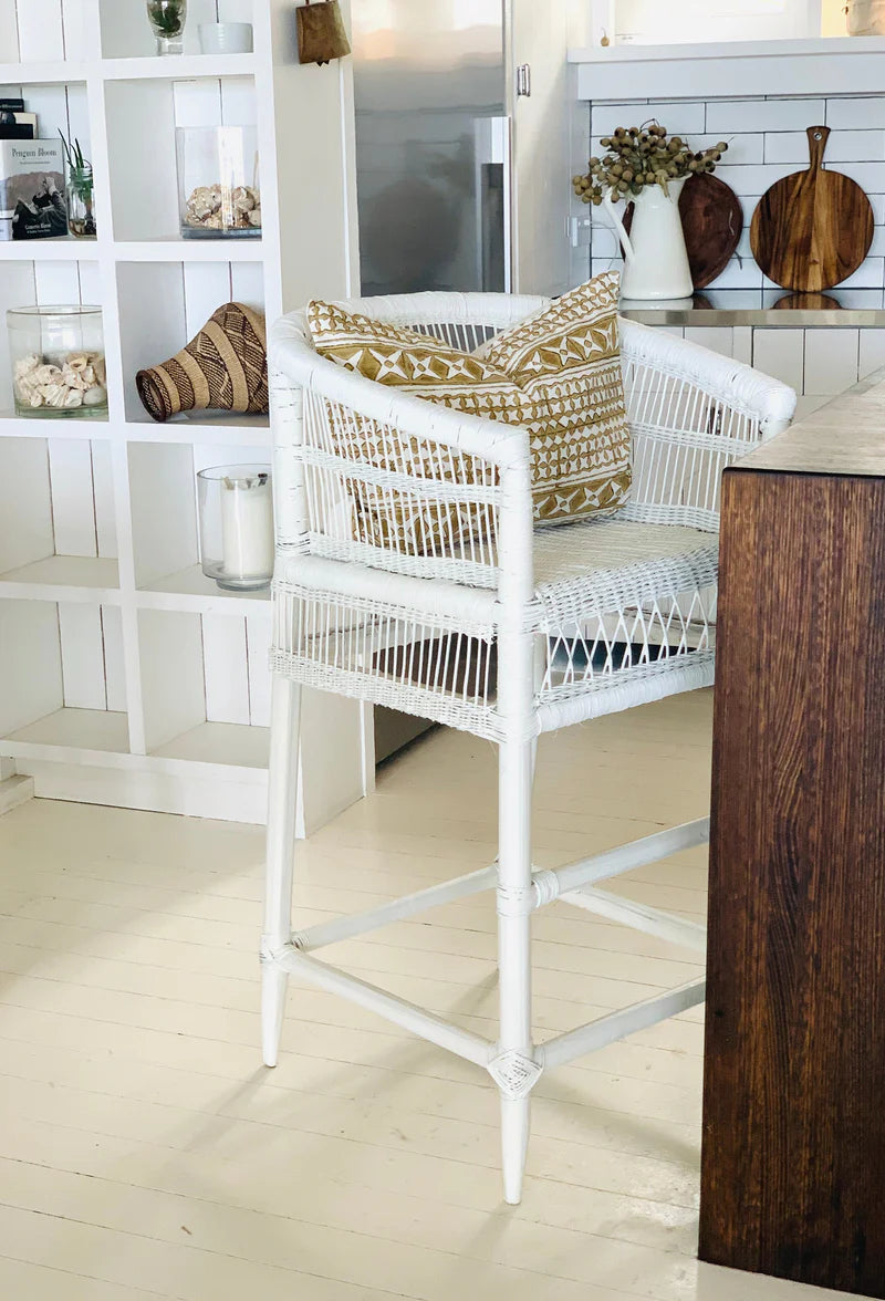 White wicker chair with patterned cushions in a room with wooden flooring and white walls.