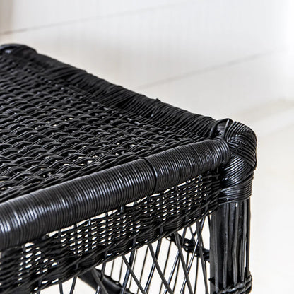 Close-up of a black wicker chair with a blurred white background