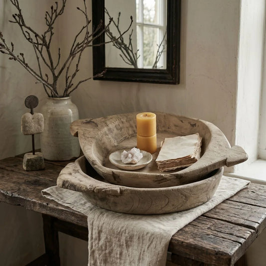 Decorative setting with wooden bowls, candle, and branches on a rustic table.