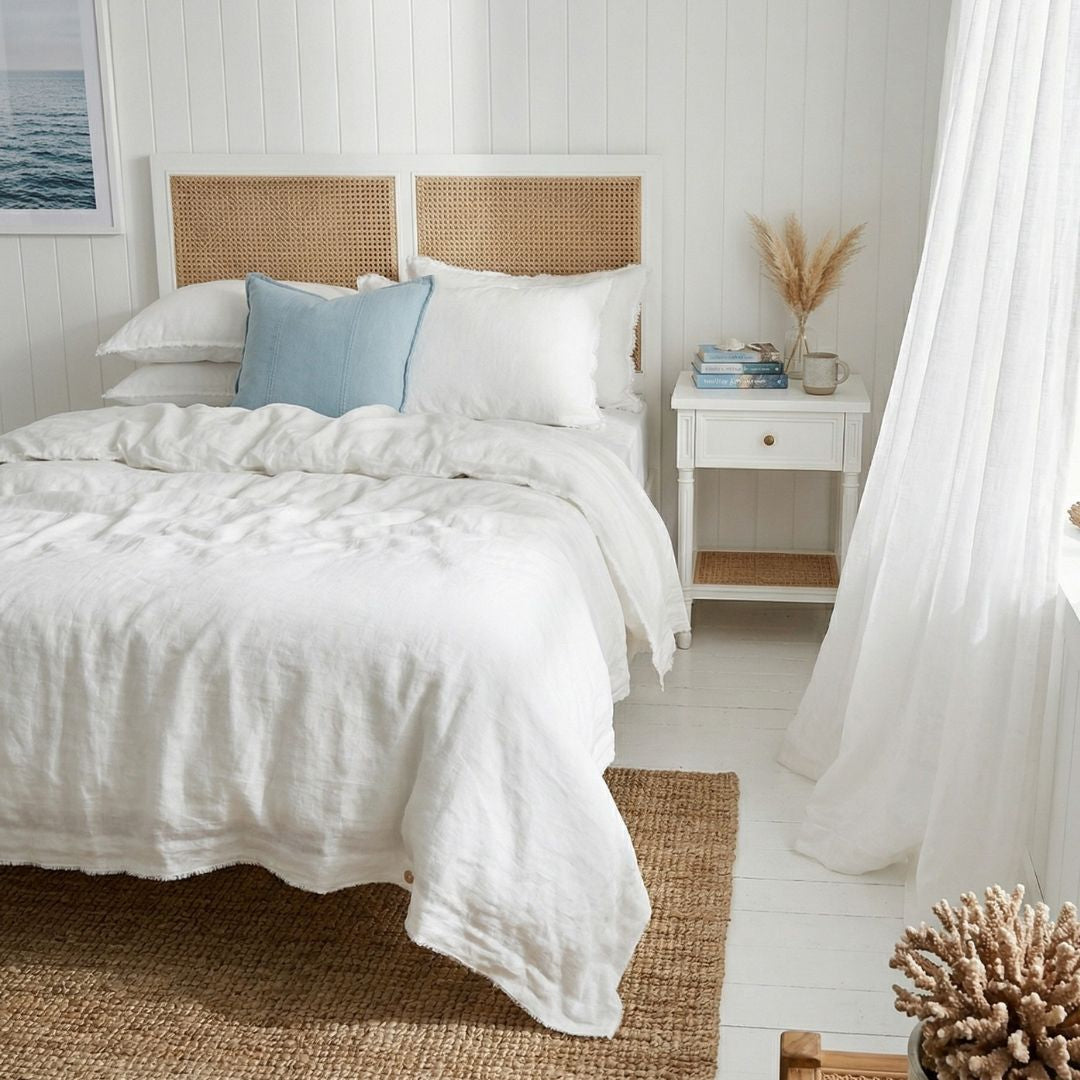 Bedroom with white bedding, wooden headboard, and white walls.
