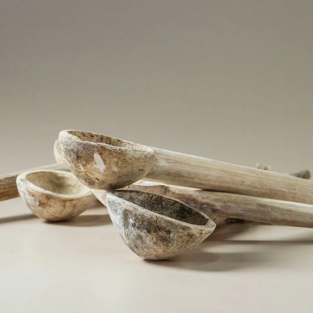 Three wooden spoons with a natural finish on a beige background