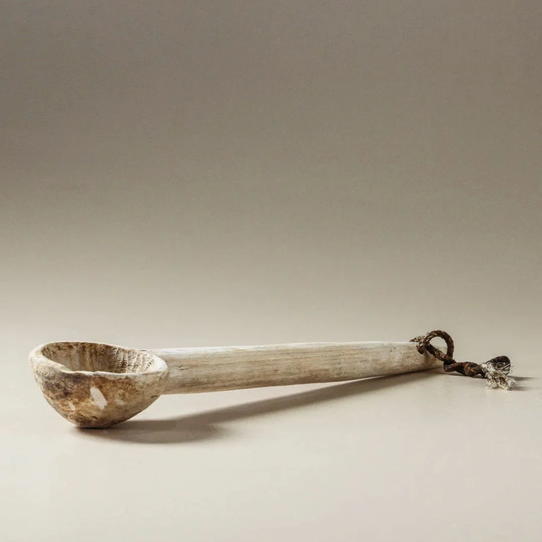 Wooden ladle with a metal handle on a beige background