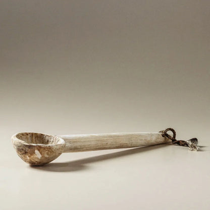 Wooden ladle with a metal handle on a beige background