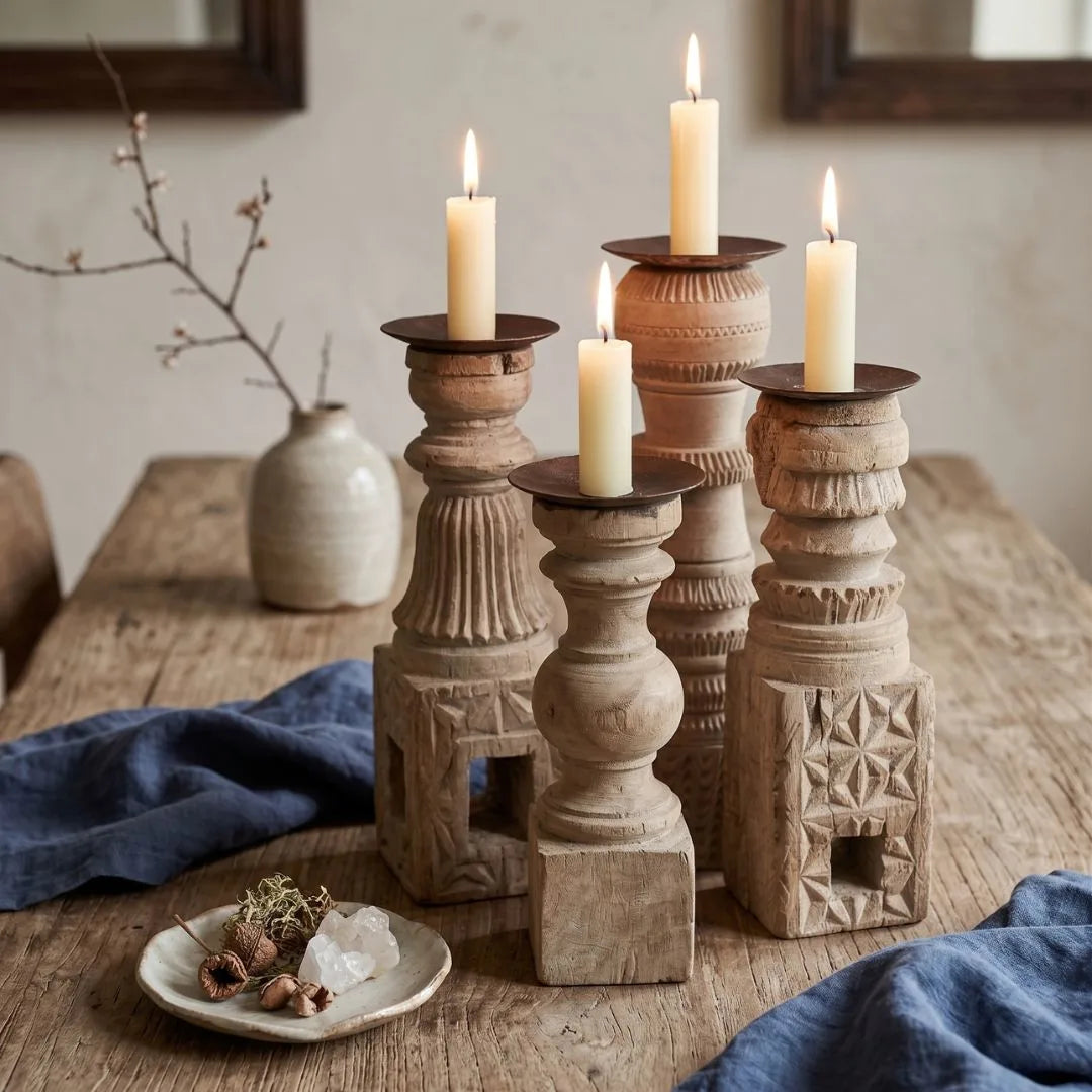 Decorative wooden candle holders with lit candles on a rustic wooden table.