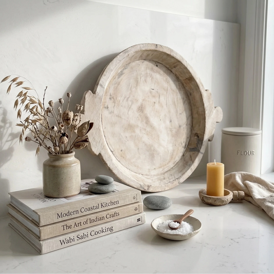 Decorative setting with a wooden tray, books, candle, and plants on a light surface.