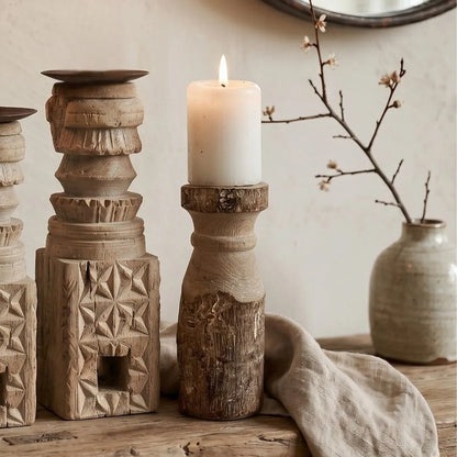 Decorative wooden candle holder with a lit candle on a rustic surface.