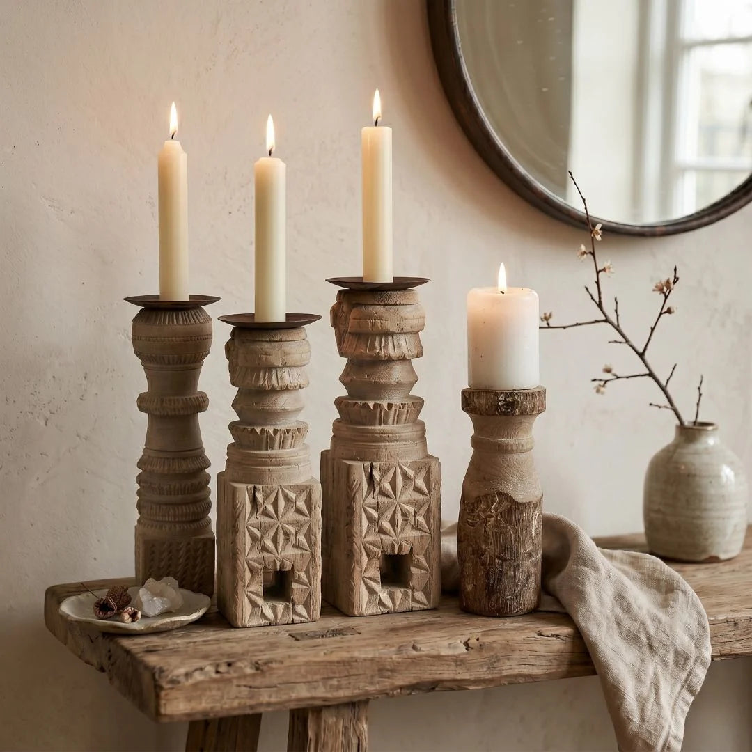 Set of wooden candle holders with lit candles on a rustic wooden surface.