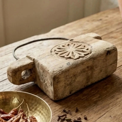 Vintage-style wooden block with decorative cutout on a wooden surface with spices.