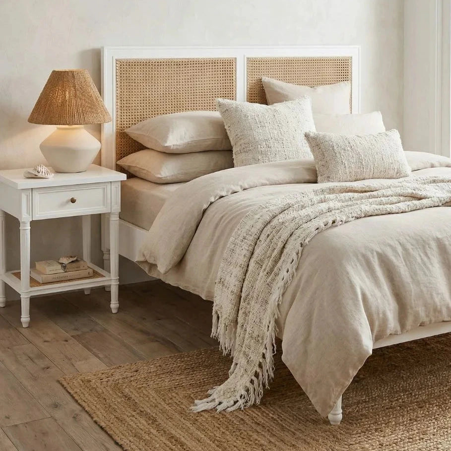 Neatly made bed with beige bedding in a bedroom setting.
