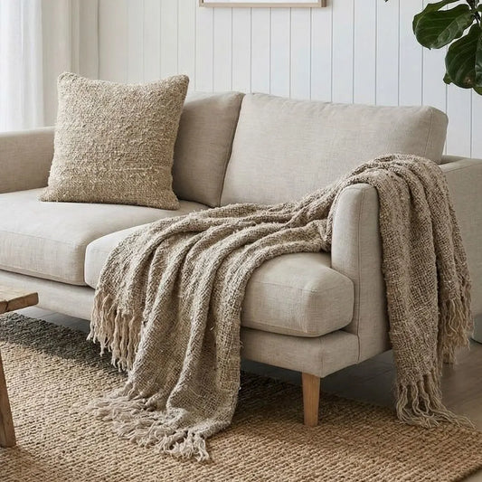 Wabi textured Natural throw blanket and matching Wabi cushion on  Beige sofa in a cozy living room.