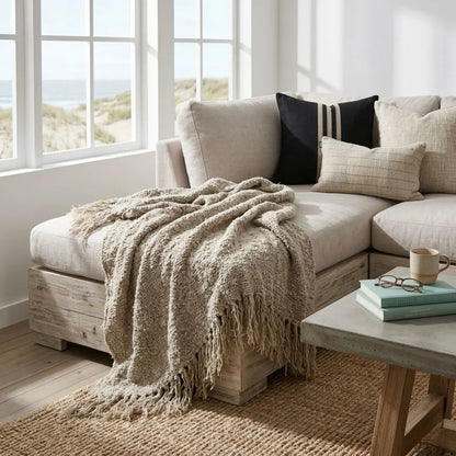 Cozy living room with a beige sectional sofa, throw blanket, and coffee table.