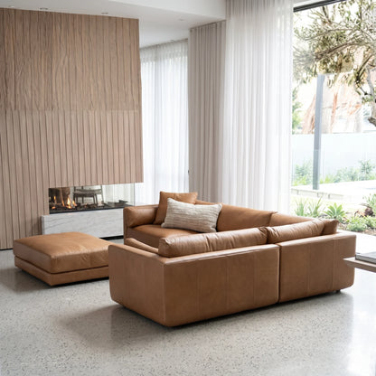 Modern living room with a brown leather sofa and ottoman.