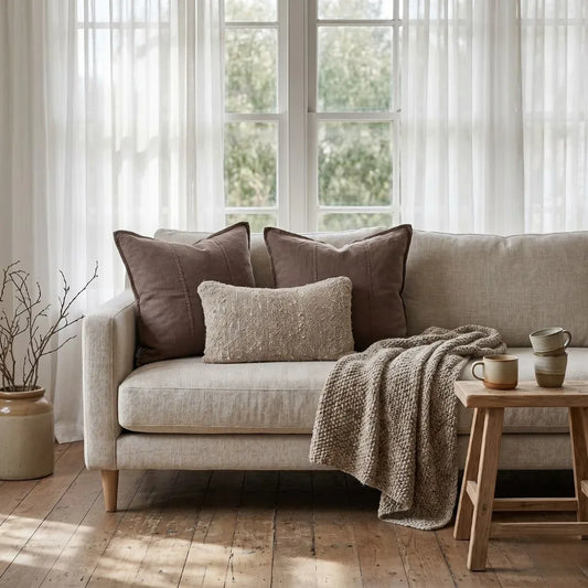 Cozy living room with a beige sofa, cushions, and a wooden side table.