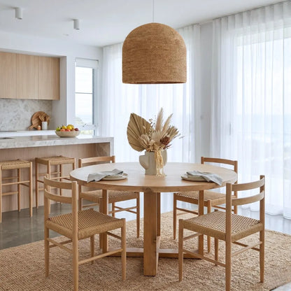 Dining area with wooden table and chairs in a bright kitchen, with large pendant