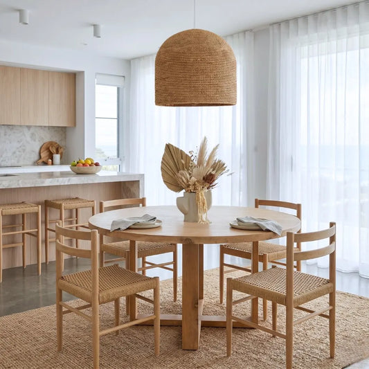 Dining area with wooden table and chairs in a bright kitchen, with large pendant