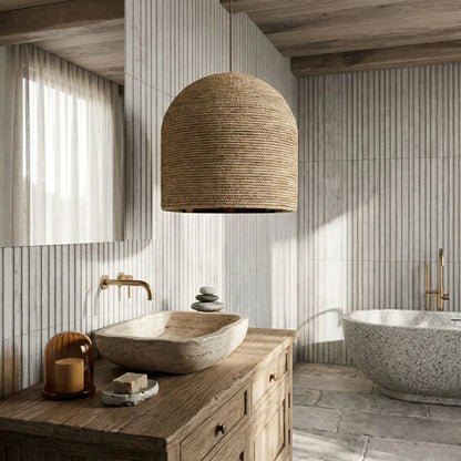 Bathroom with wooden vanity, stone sink, and wicker pendant light.