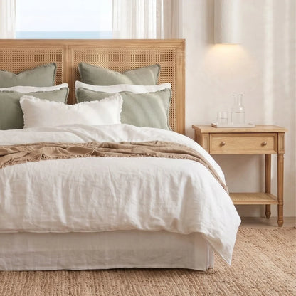 Neatly made bed with beige and white bedding in a bedroom setting.