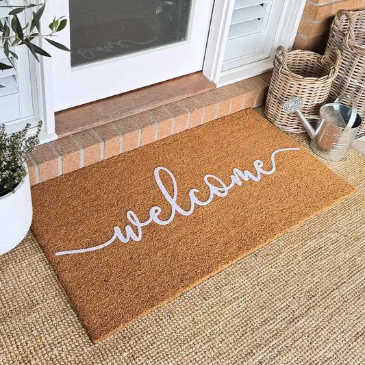 Doormat with 'welcome' text on a carpeted floor in front of a door.